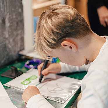 Auf dem Bild ist ein Junge zu sehen, welcher etwas auf einer Folie nachzeichnet.