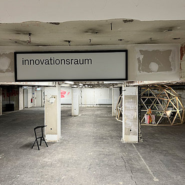 Der innovationsraum der gläsernen werkstatt mit dem Schild "innovationsraum" an einem Deckenvorsprung.